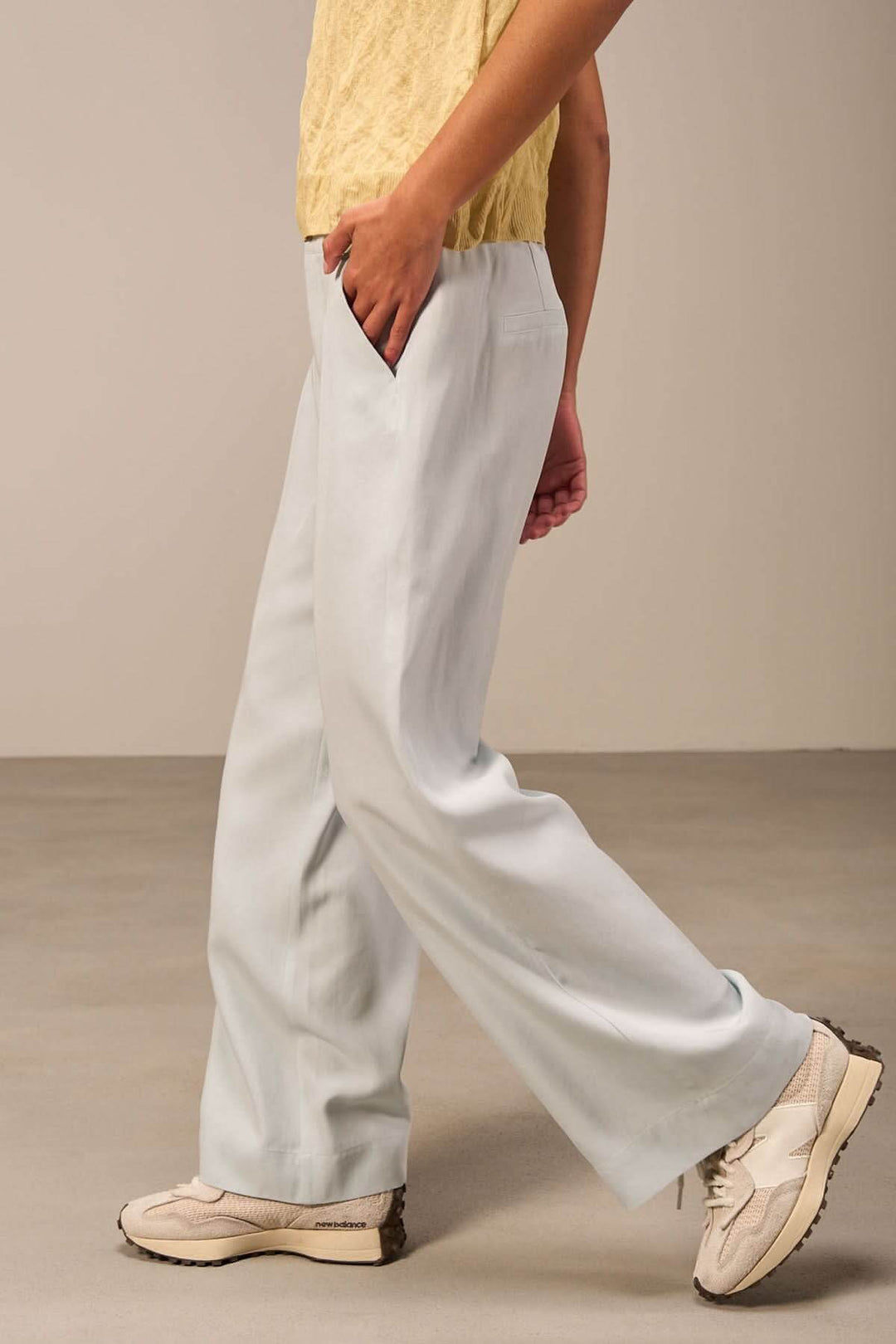 Pantalon ample bleu clair avec poches, taille haute, porté avec un haut noir et des chaussures décontractées.