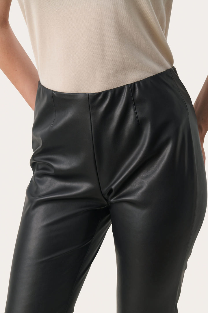 Pantalon Lorenza noir en simili cuir avec coupe légèrement évasée et taille haute élastiquée, alliant confort et style.