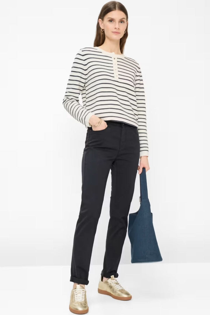 Femme portant le Pantalon MARY coupe droite avec poches, associé à un haut rayé et des chaussures dorées.
