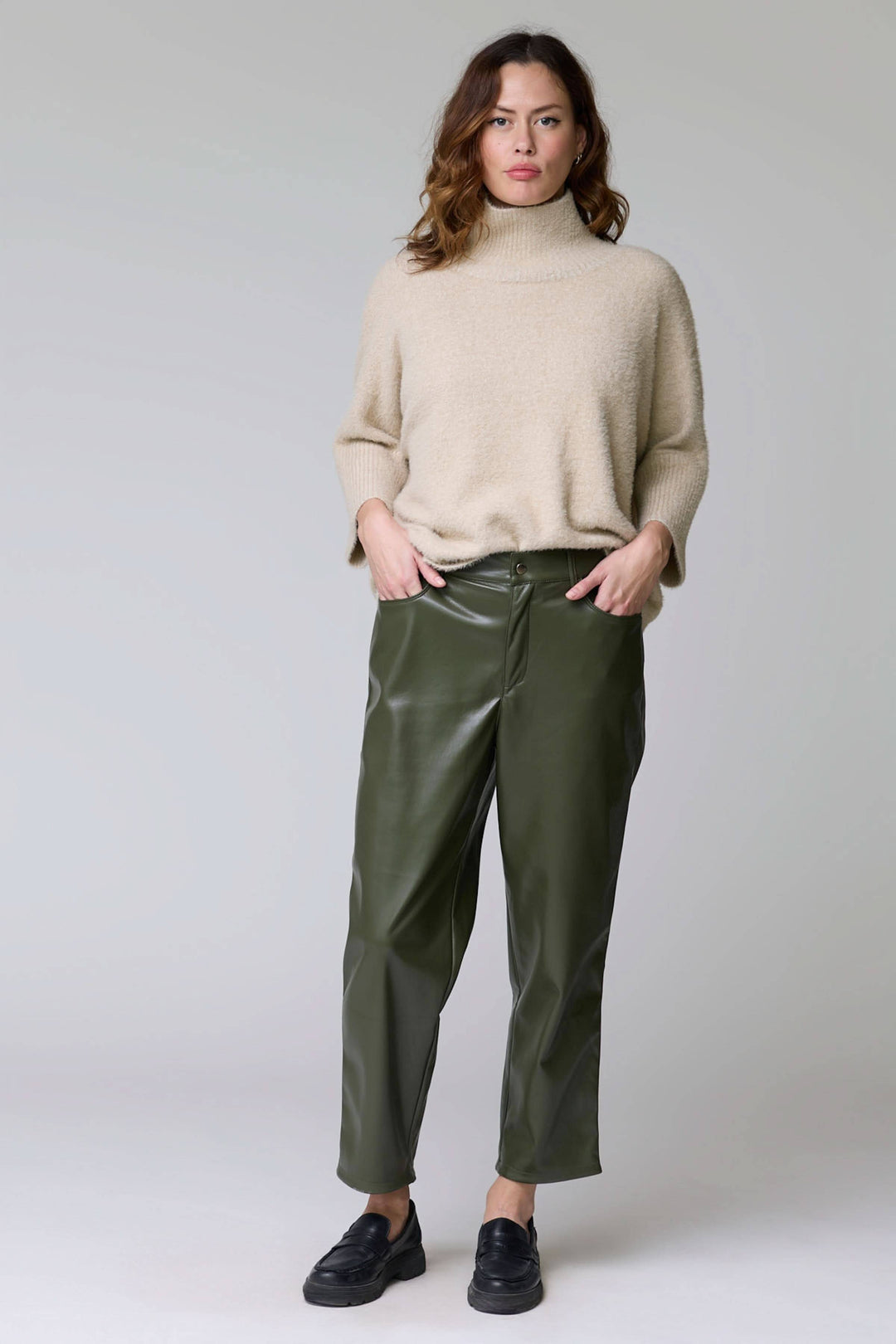 Femme portant Pantalon Sabrna effet cuir vert avec coupe droite et texture lustrée, look urbain chic et moderne.