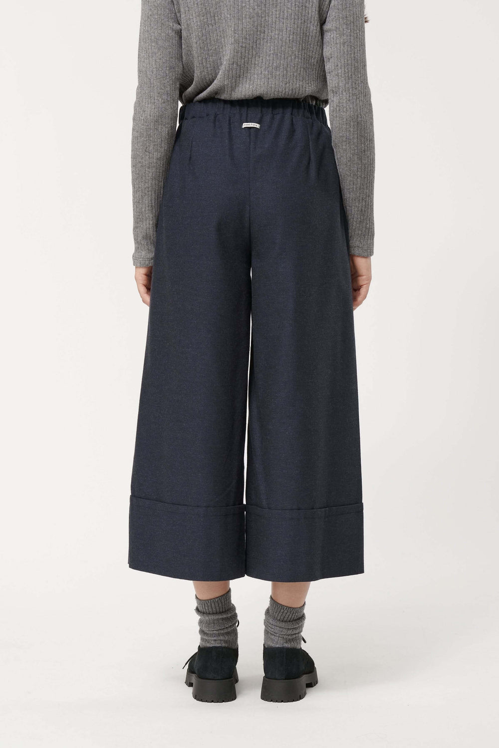 Pantalon Sophio ample façon culotte, coupe large et fluide, taille élastique, style urbain avec chaussures noires et chaussettes grises.