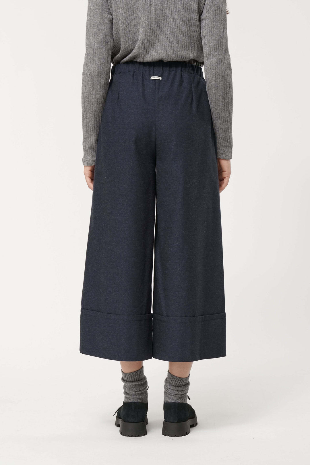 Pantalon Sophio ample façon culotte, coupe large et fluide, taille élastique, style urbain avec chaussures noires et chaussettes grises.