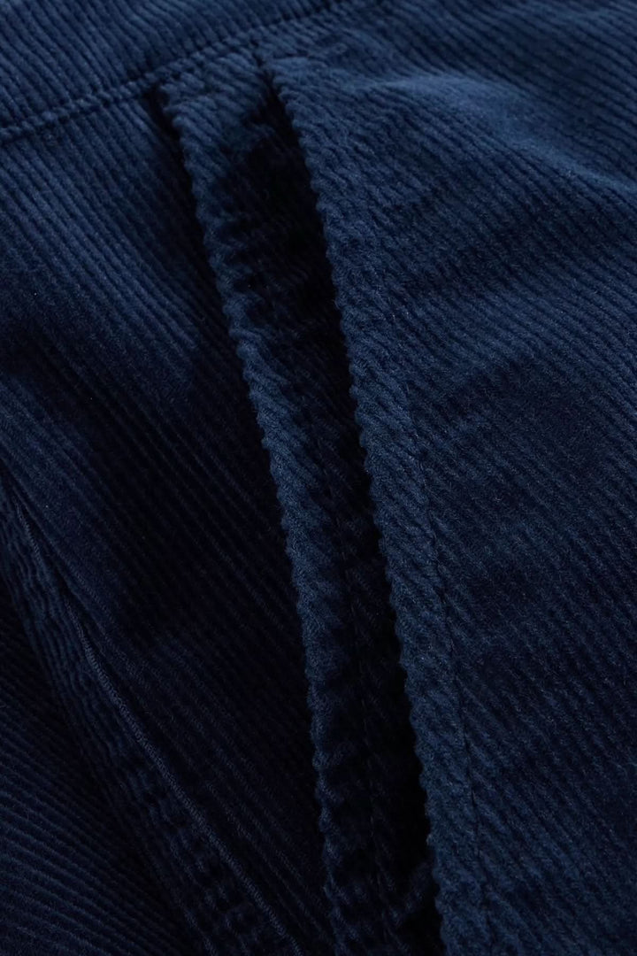 Gros plan sur le tissu velours côtelé bleu du Pantalon Twister, montrant la texture et la qualité du textile.