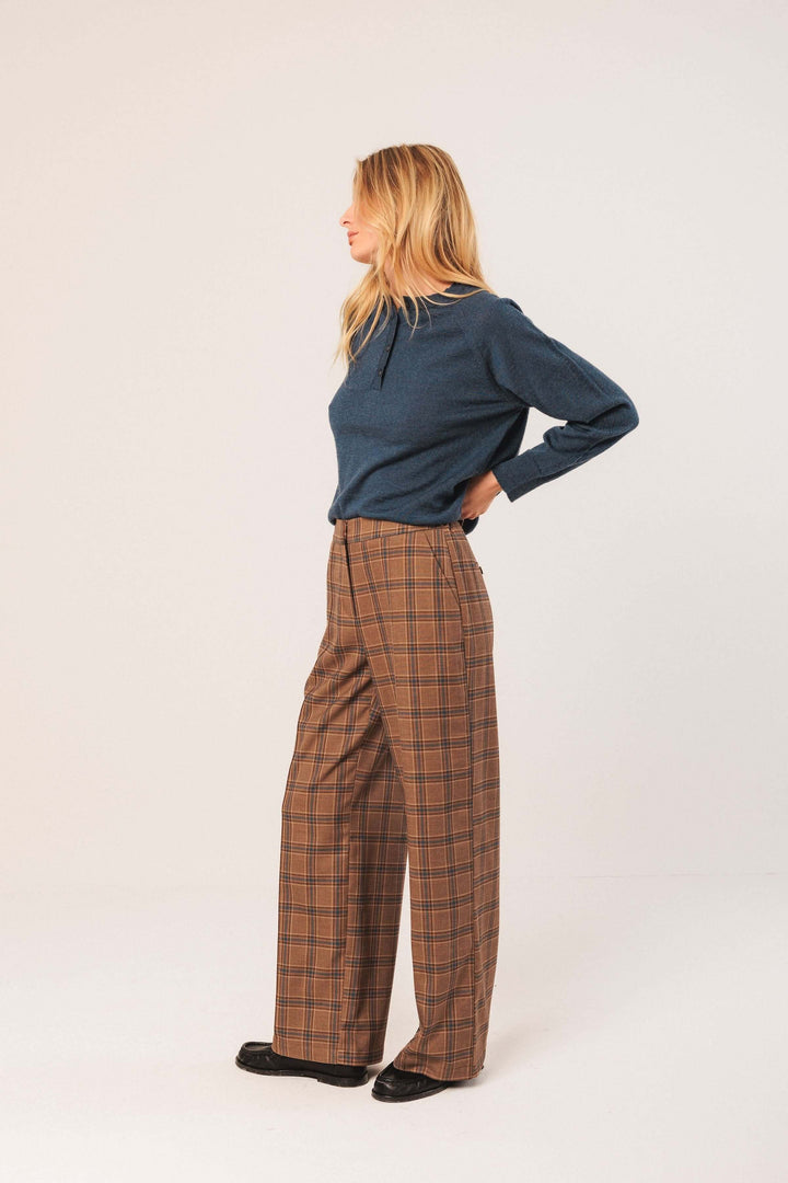 Femme portant un pantalon à carreaux à coupe large et fluide, idéal pour une tenue chic et moderne avec motif intemporel.
