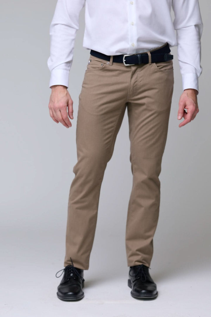 Pantalon chino extensible en tissu doux, coupe ajustée, idéal pour bureau ou sorties décontractées, porté avec chemise blanche.