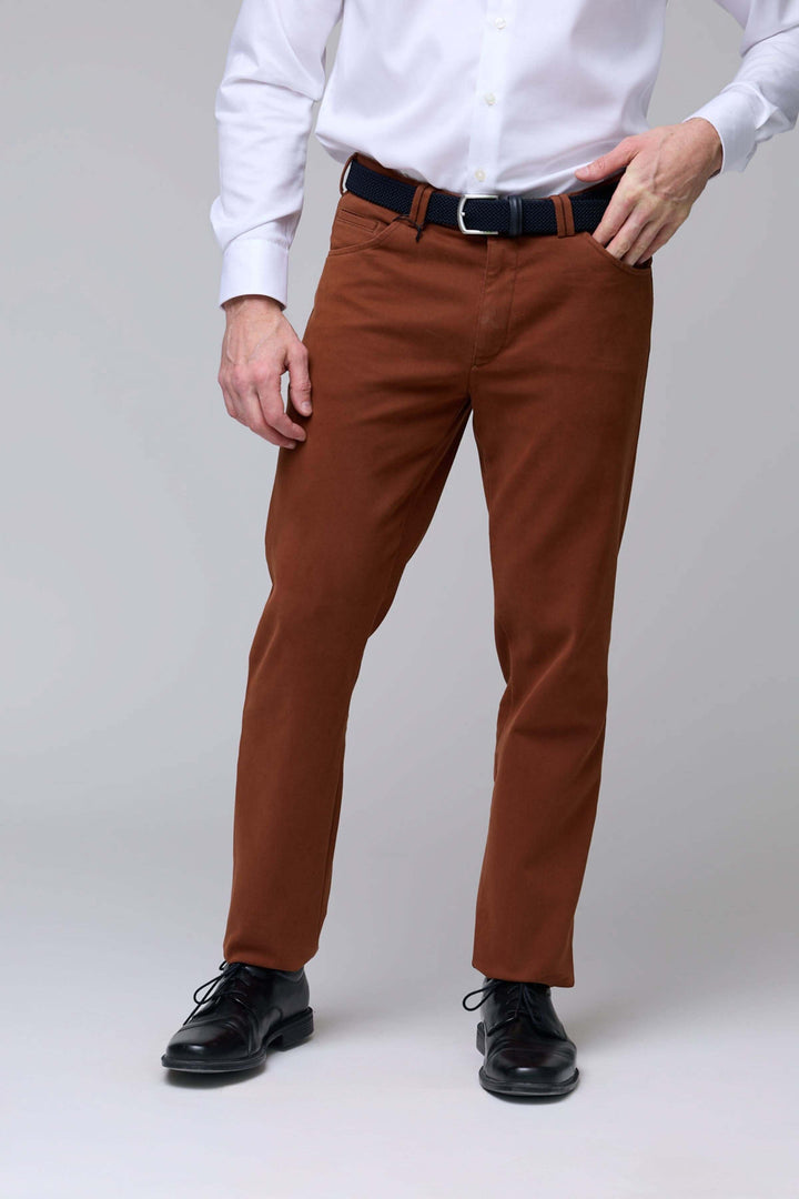 Homme portant un pantalon chino moderne marron avec chemise blanche et chaussures noires.