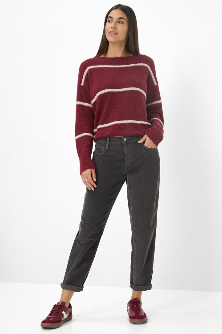 Femme portant un Pantalon de style Mary coupe décontractée, taille mi-haute, jambes fuselées, avec pull ample et baskets rouges.