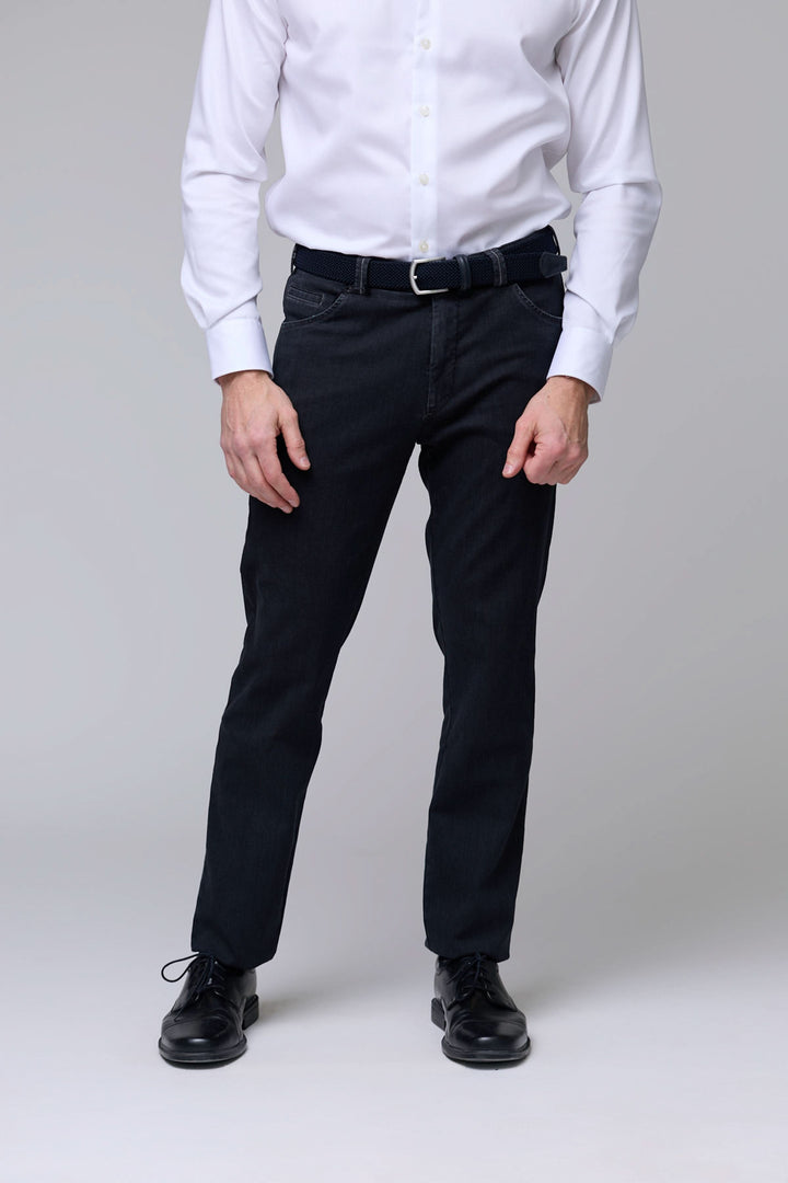 Homme portant un pantalon denim extensible noir, coupe ajustée avec cinq poches et finitions ton sur ton pour un style raffiné.