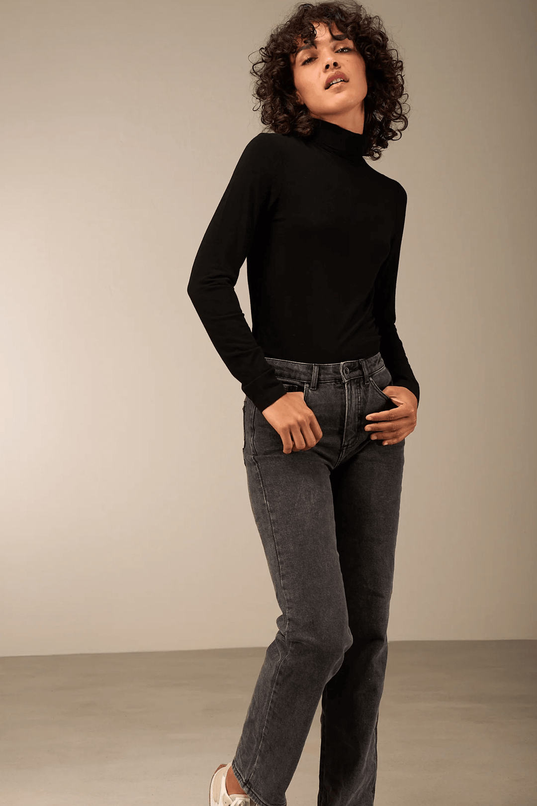 Femme portant un pantalon droit noir avec coupe décontractée et chandail ajusté, reflétant confort et style intemporel.