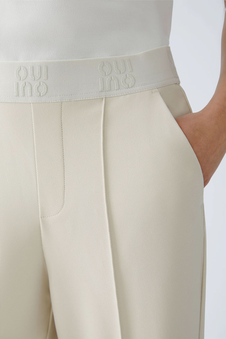 Pantalon droit à taille élastique logo avec plis marqués et poches latérales, parfait pour une allure structurée et moderne.