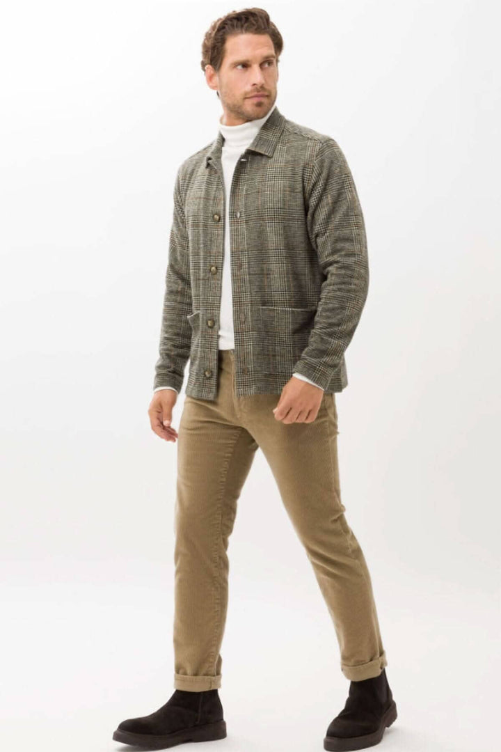 Homme en pantalon corduroy beige et veste à carreaux, look décontracté chic, chaussures noires.