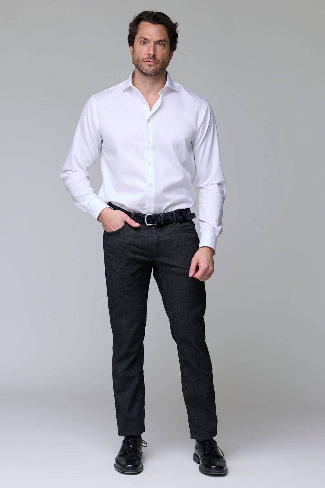 Homme portant un pantalon en laine extensible et une chemise blanche, coupe moderne et élégante, idéal pour le bureau.