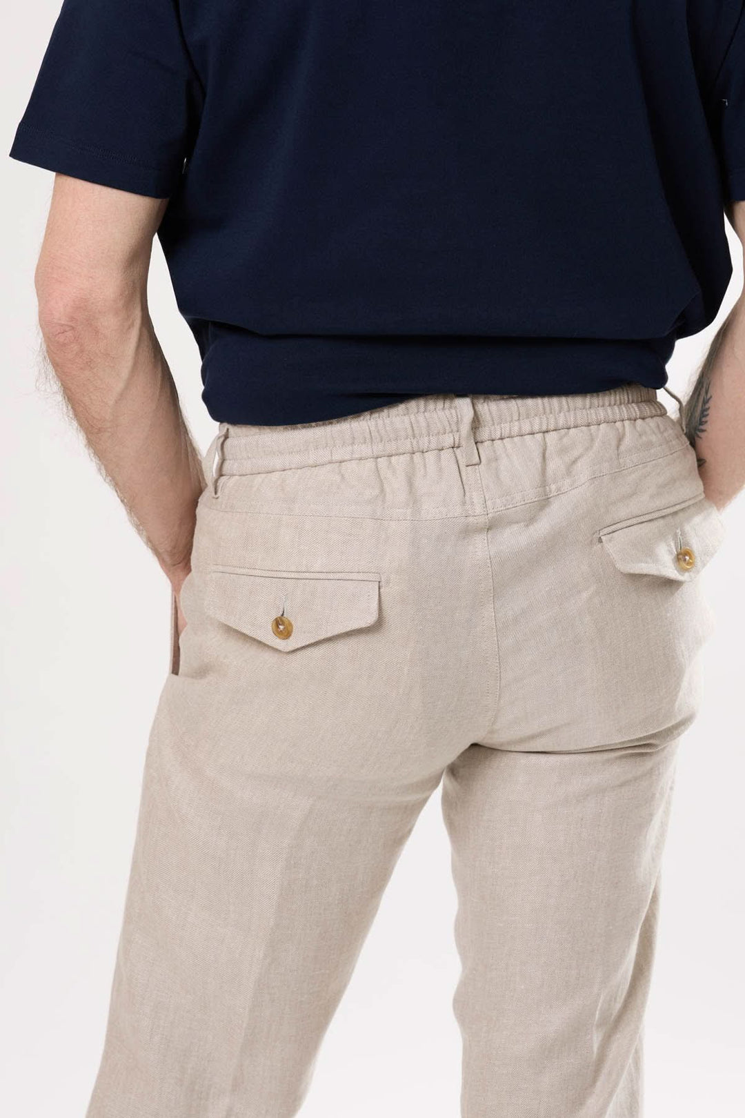 Pantalon en lin beige à taille élastique avec poches latérales et détails structurés, porté par un homme.