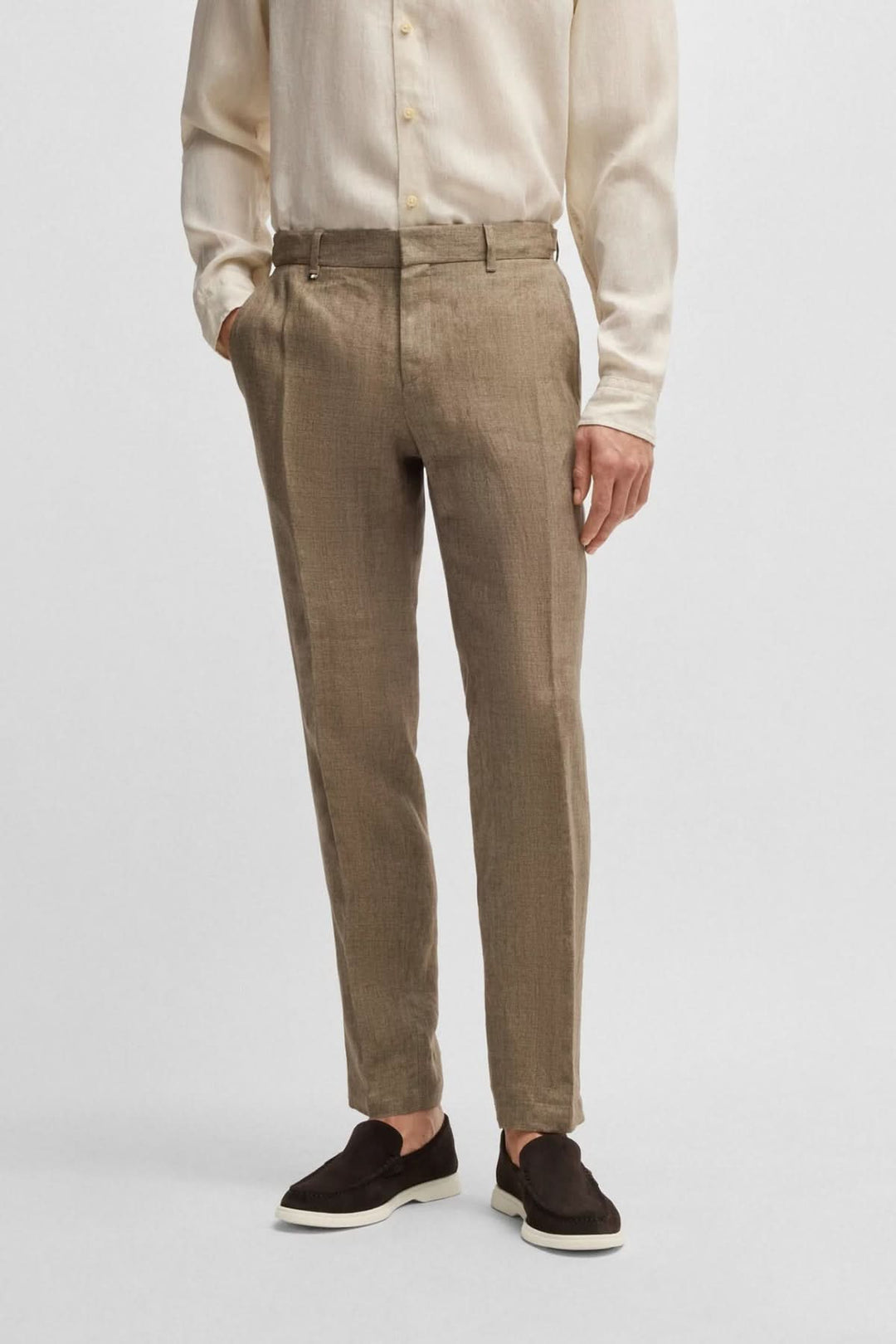 Pantalon en lin beige ajusté avec chaussures noires et chemise claire, style élégant et décontracté.