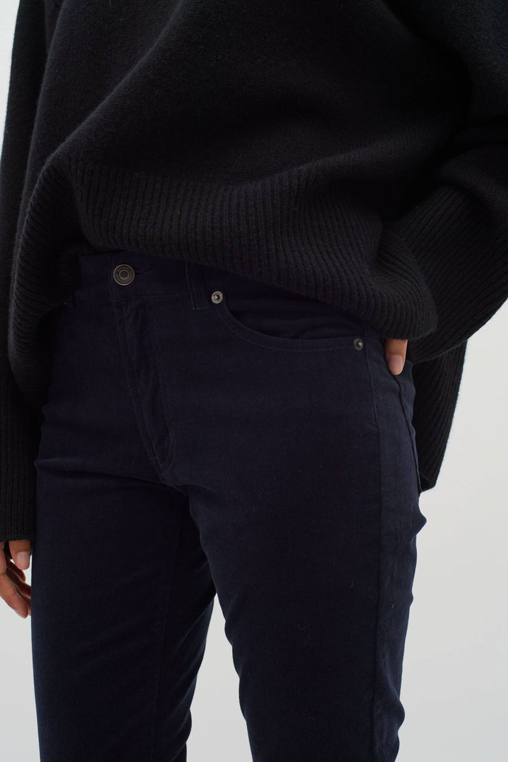 Pantalon en velours bleu marine porté avec un pull noir, idéal pour l&