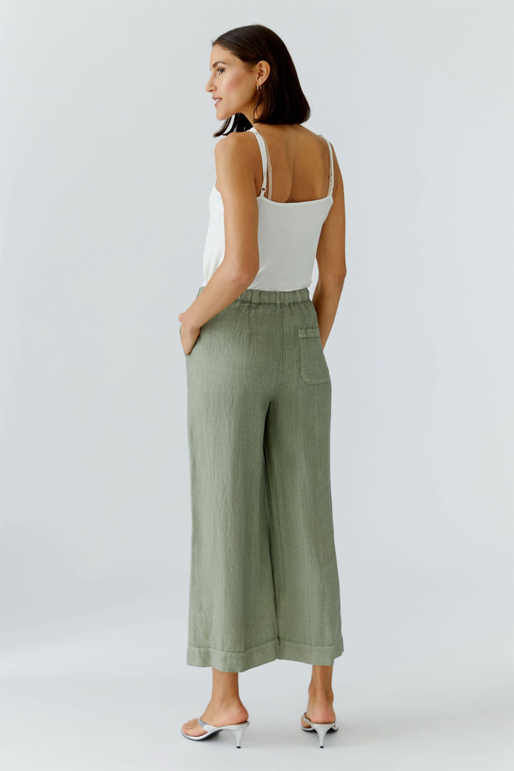 Femme portant un pantalon fluide en lin à jambe large vert, taille élastiquée, vue arrière.