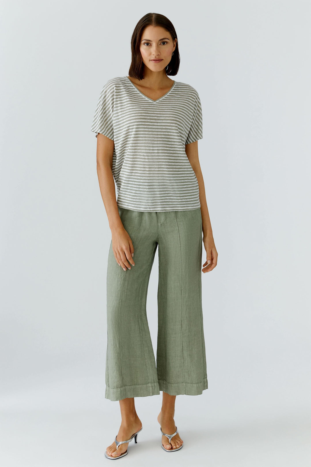 Femme portant un pantalon fluide en lin à jambe large avec un t-shirt rayé, parfait pour un look moderne et décontracté.
