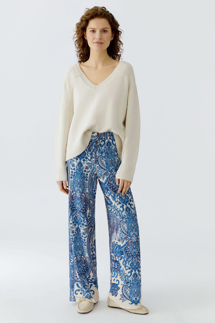Modèle portant un pantalon fluide à imprimé cachemire avec chandail crème au look bohème.
