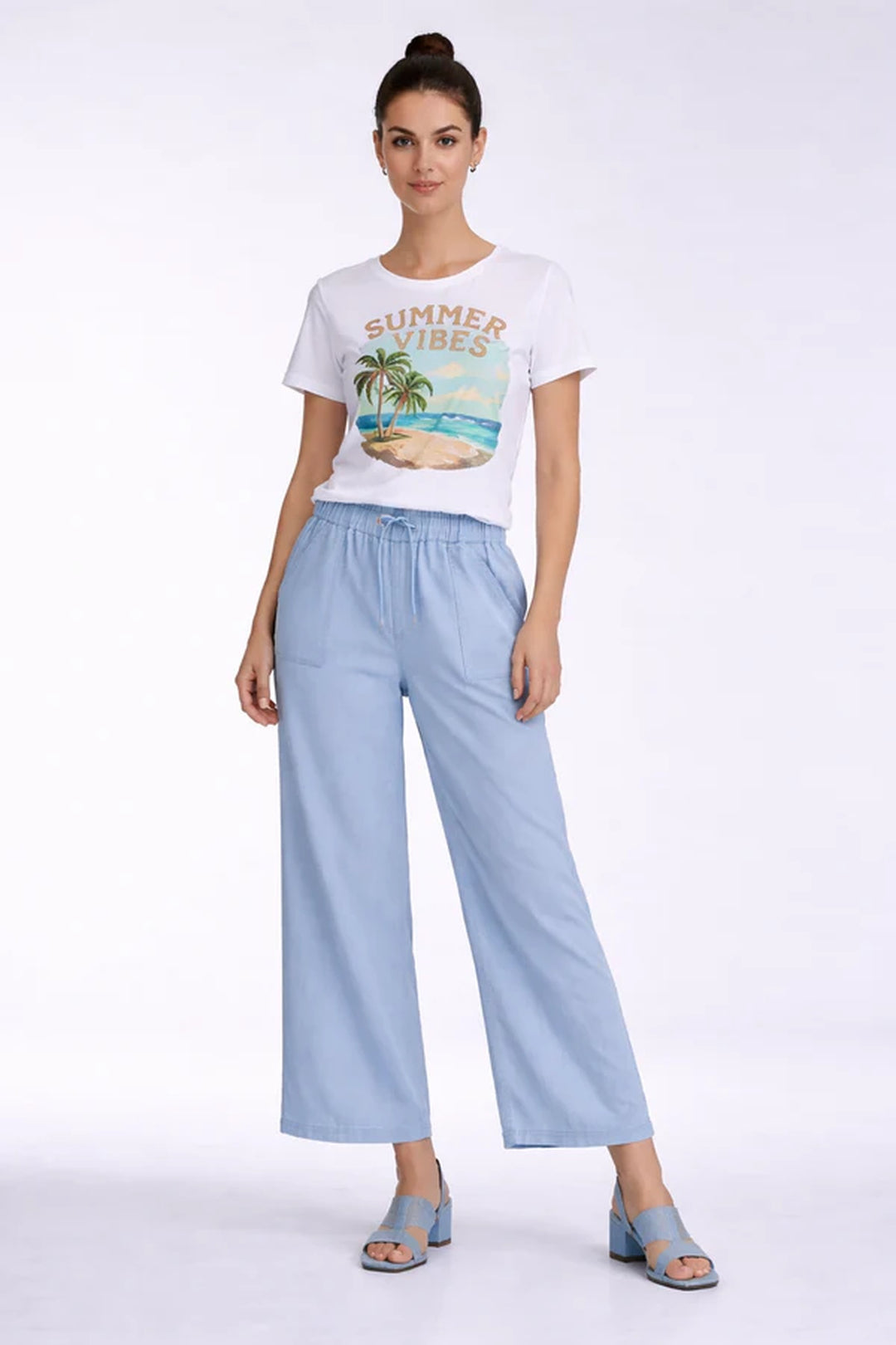 Femme portant un pantalon fluide taille élastique à cordon, coupe large et longueur raccourcie, avec un t-shirt "Summer Vibes".