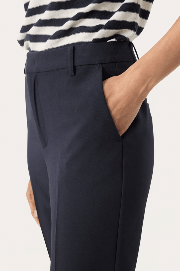 Détail d'un pantalon habillé bleu marine avec poches en biais et coupe élégante.
