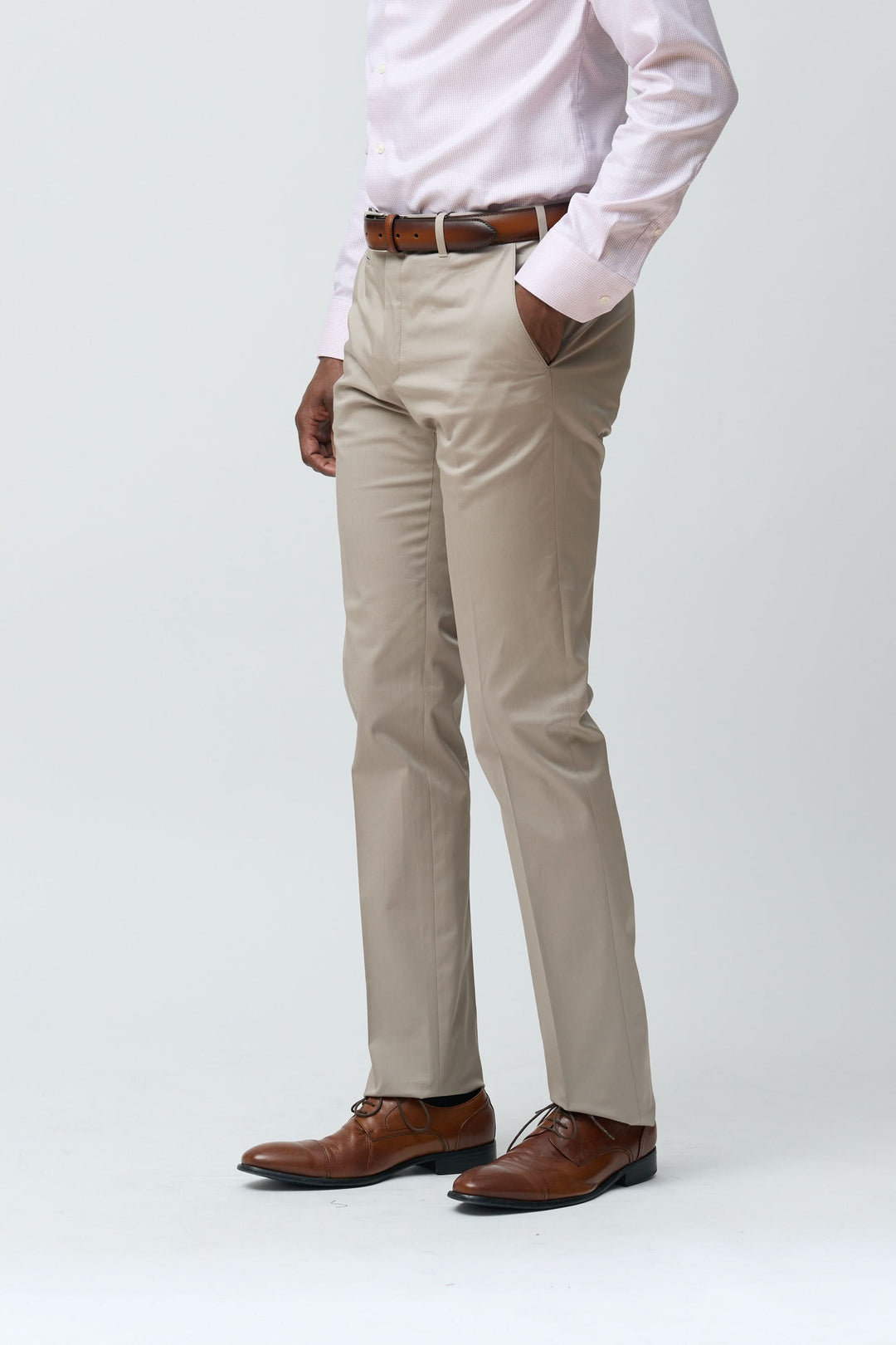 Homme portant un pantalon habillé coupe ajustée beige, associé à une chemise blanche, idéal pour un look professionnel ou décontracté.