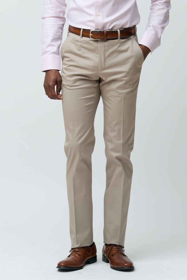 Homme portant un pantalon habillé coupe ajustée beige avec ceinture marron et chaussures élégantes.