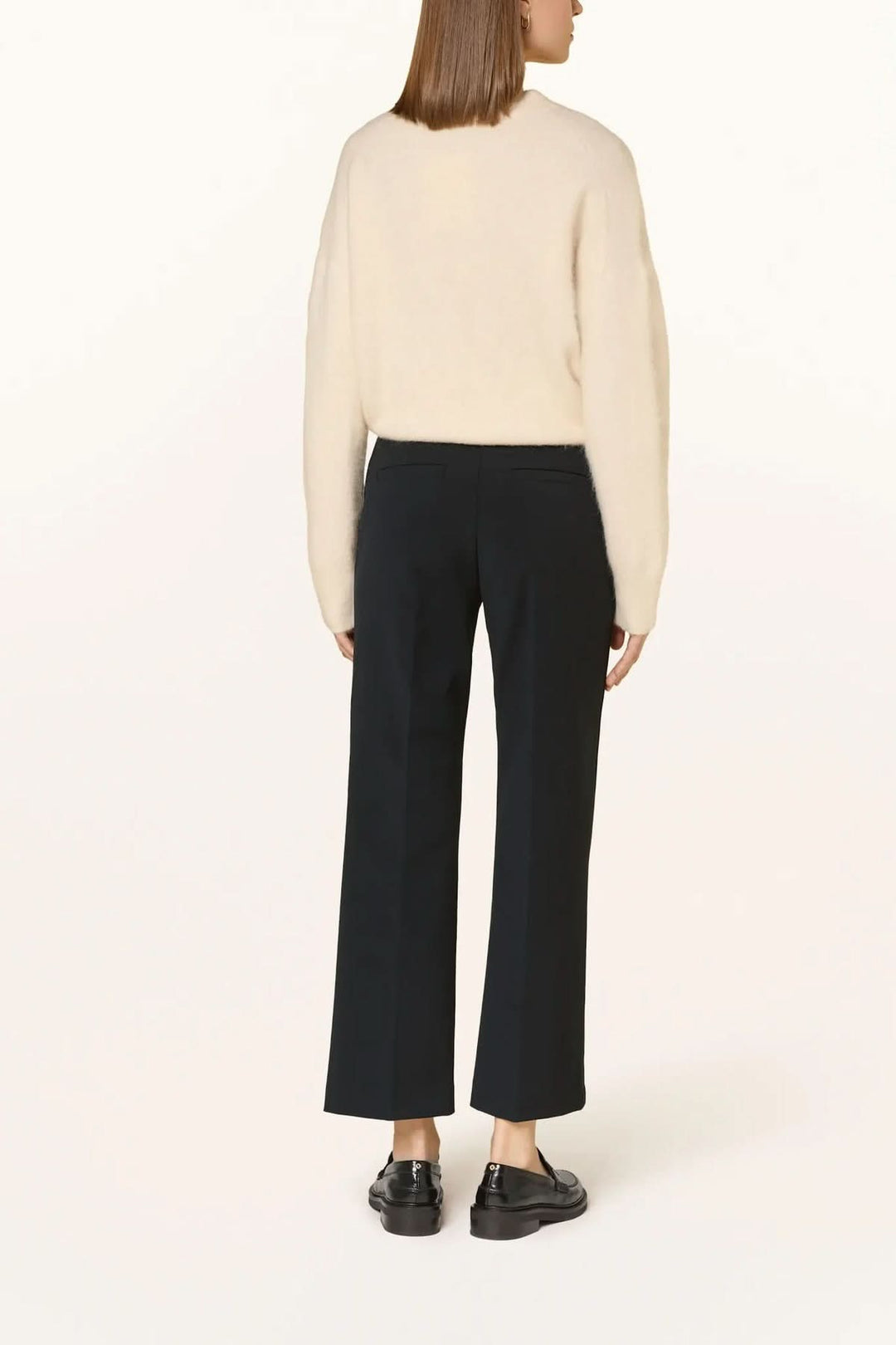 Pantalon habillé coupe droite à plis marqués vu de dos, montré avec un chandail fin, en style bureau.