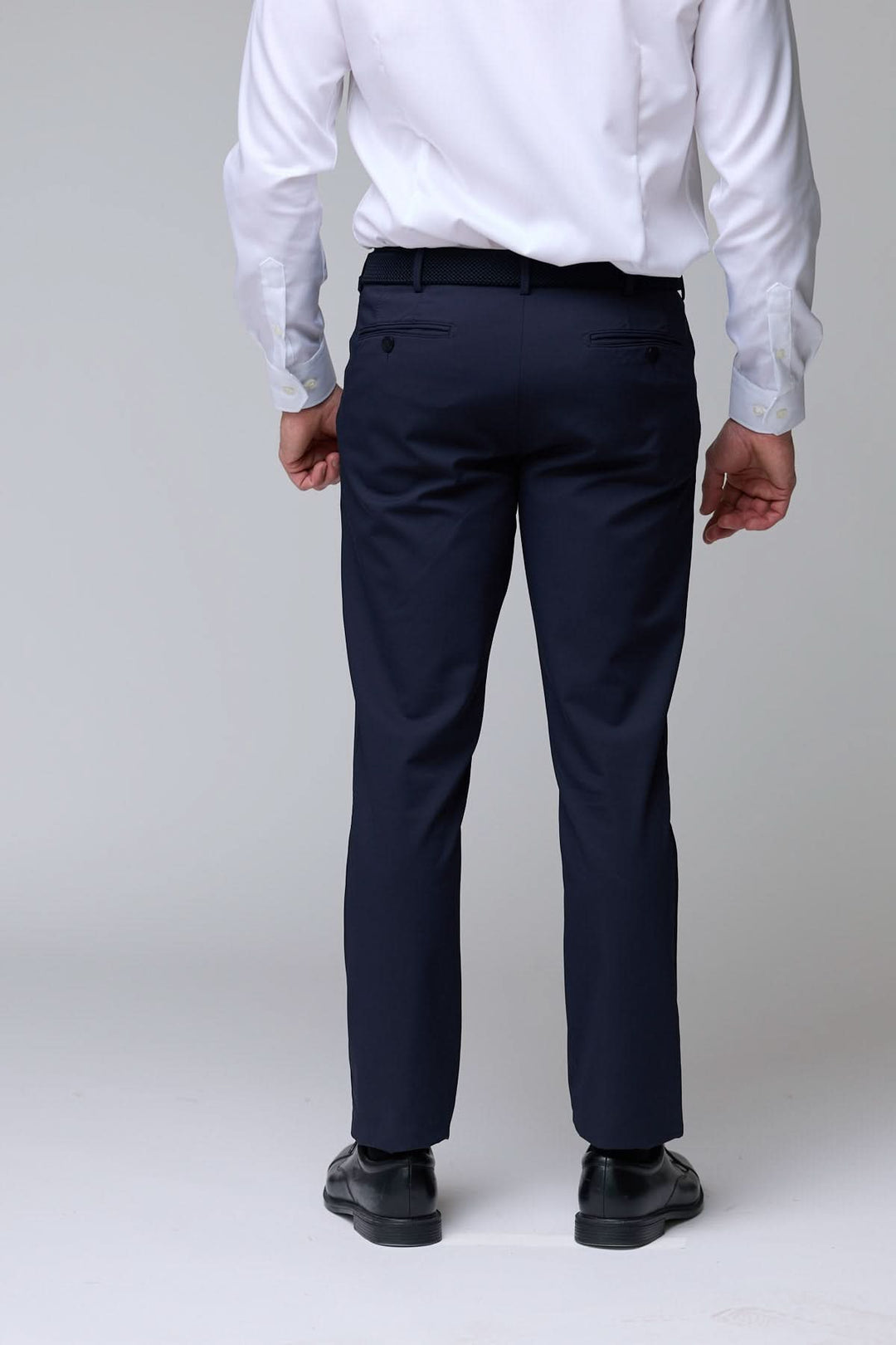 Homme portant un pantalon habillé extensible bleu marine élégant vu de dos, stylé et moderne.