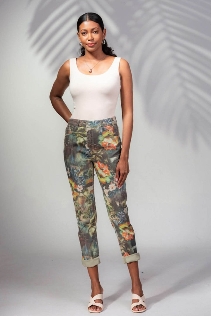 Femme souriante portant un pantalon imprimé tropical avec un haut uni et des sandales, look estival.