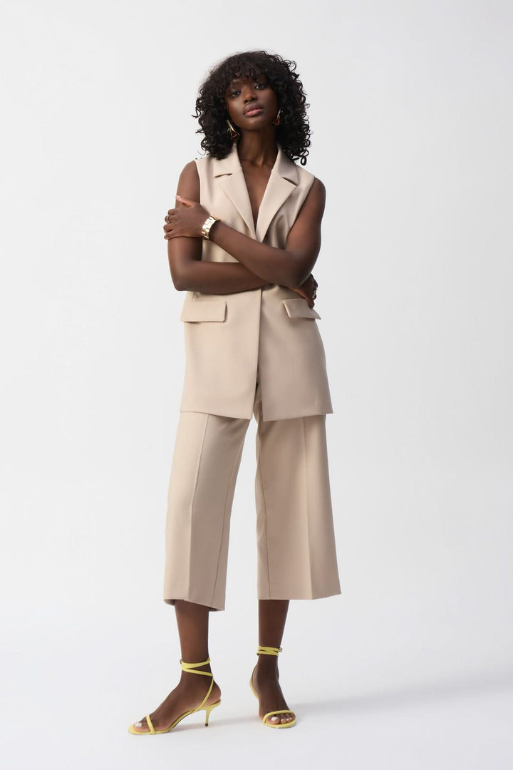 Femme portant un pantalon à jambe large beige et un gilet sans manches, look élégant et décontracté.