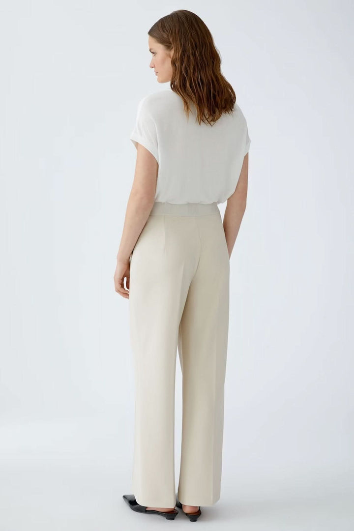 Femme portant un pantalon à jambe large en jersey technique avec ceinture élastique, vue arrière. Parfait pour une silhouette allongée.