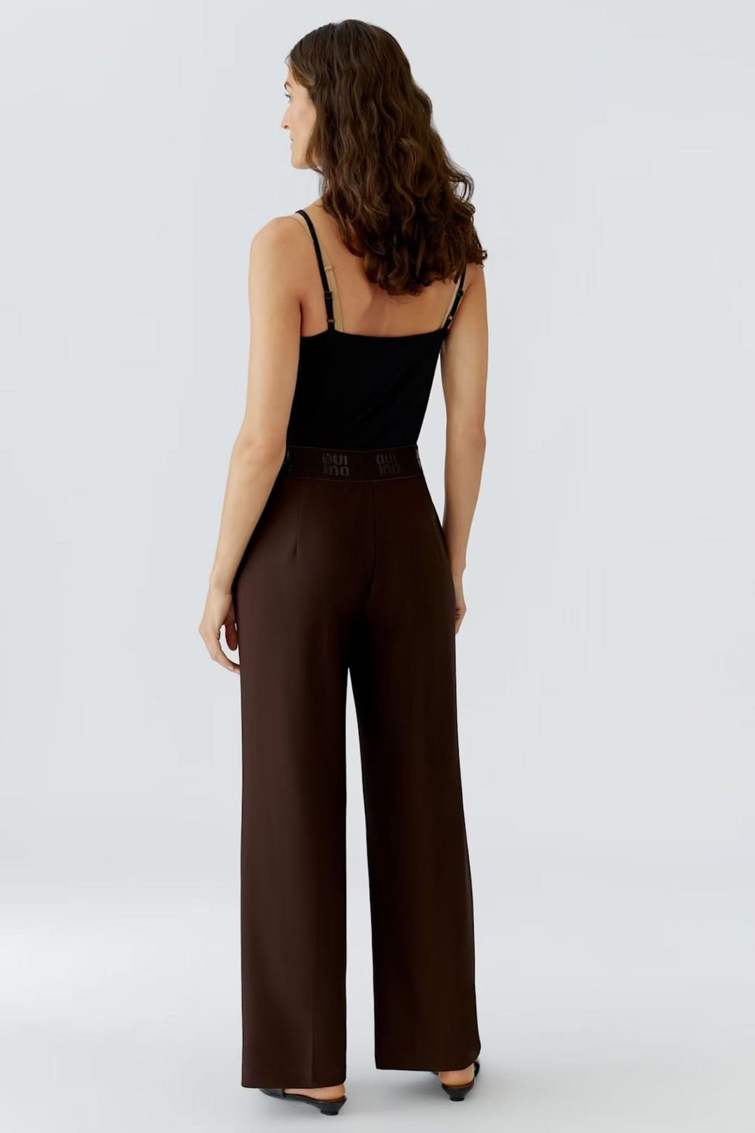 Femme portant un pantalon à jambe large en jersey technique avec ceinture élastique, vue de dos, pour un style élégant et confortable.