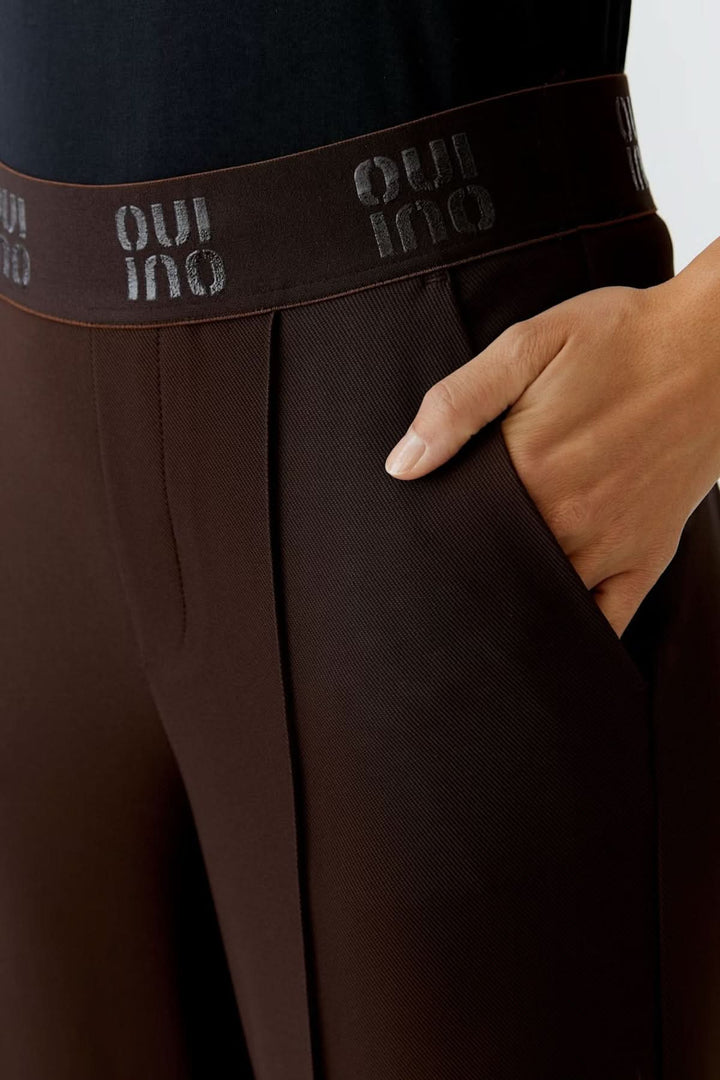 Pantalon à jambe large en maille technique marron avec ceinture élastique logo, design chic et confortable.