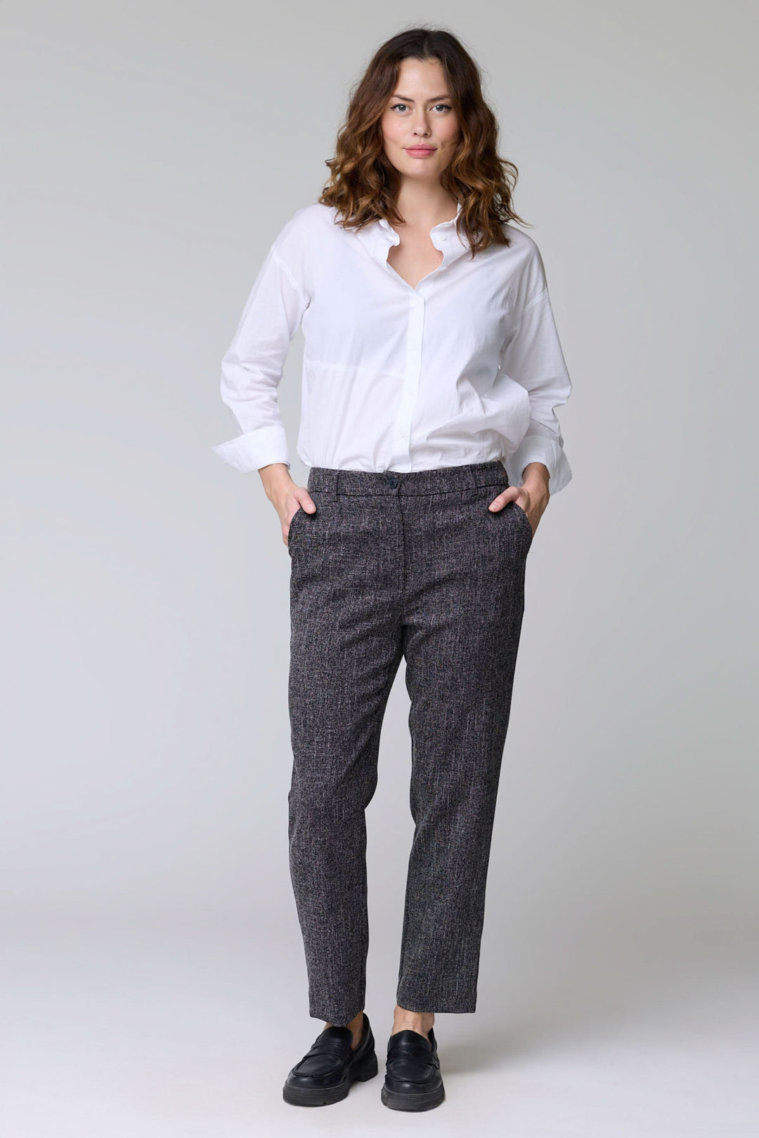 Femme portant un pantalon à motif texturé avec coupe droite et tissu extensible, parfait pour le bureau ou les sorties.