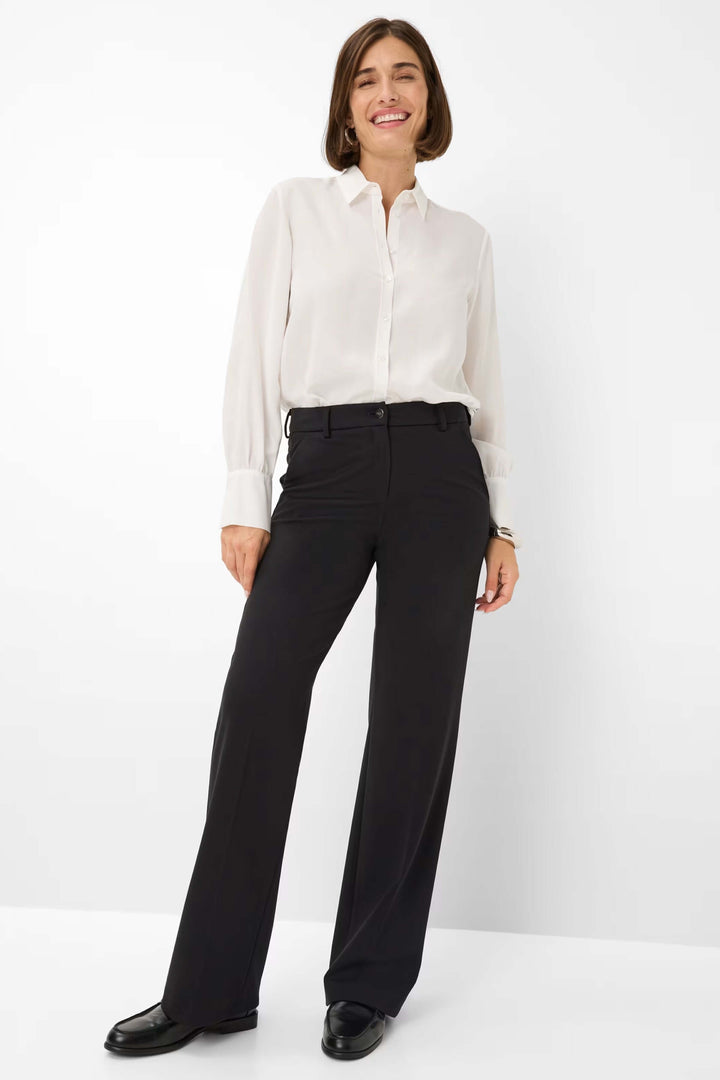 Femme portant un pantalon palazzo noir avec chemise blanche pour un style chic et confortable.
