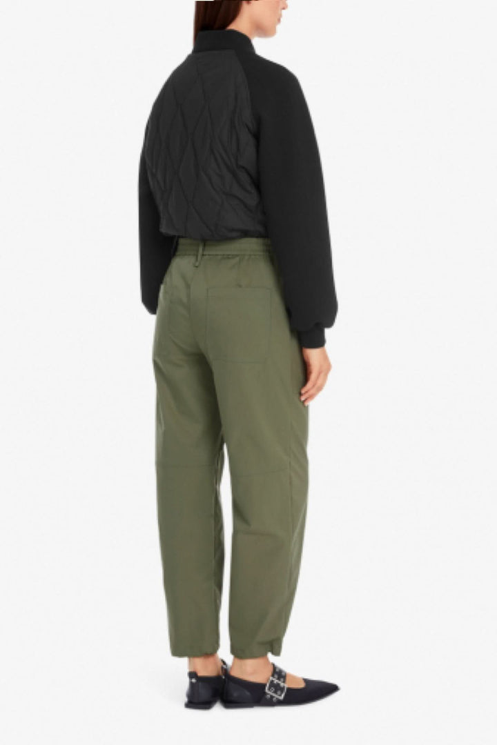 Femme vue de dos portant un pantalon style aviateur vert avec un bomber noir et des chaussures élégantes.
