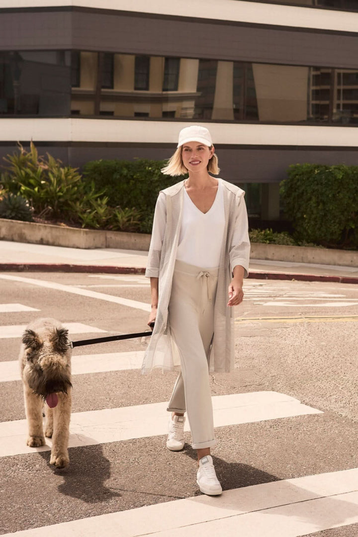 Femme marchant en ville avec chien, portant un pantalon à taille nouée coupe droite, tenue moderne et confortable.