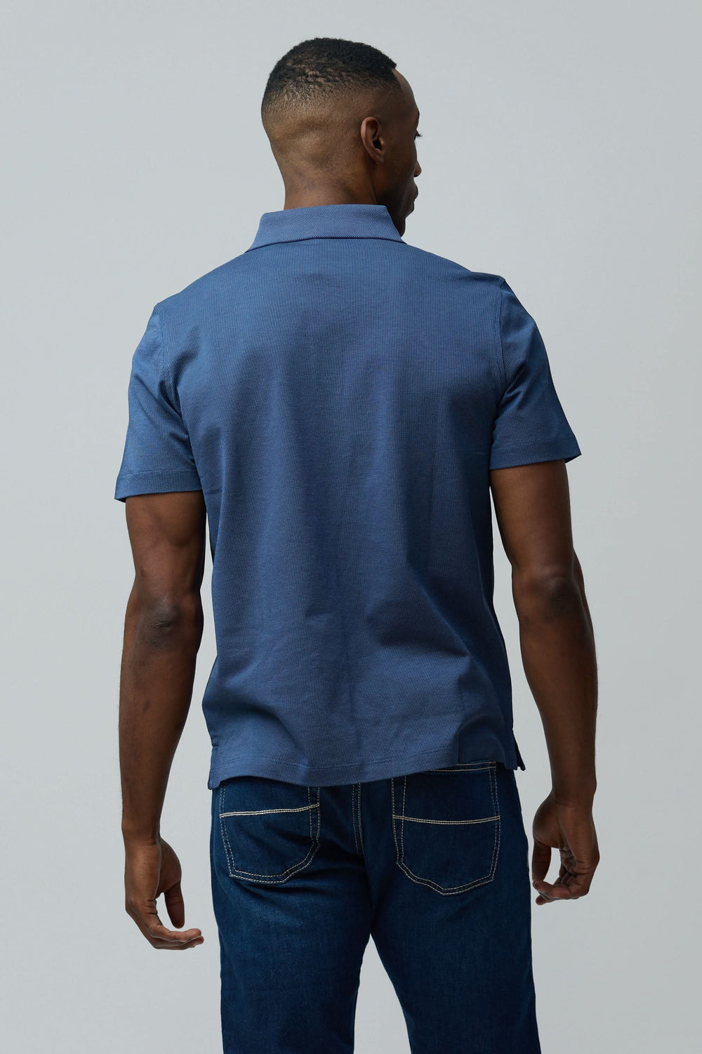 Homme portant un Polo en coton Corneliani bleu à manches courtes vu de dos, élégant et décontracté, coupe ajustée.