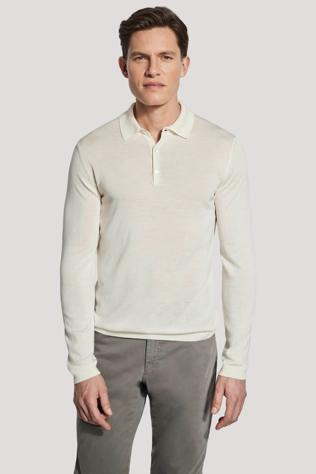 Polo manches longues en laine mérinos et soie pour homme, élégant et confortable, porté par un modèle. Maille fine calibre 14, style moderne.