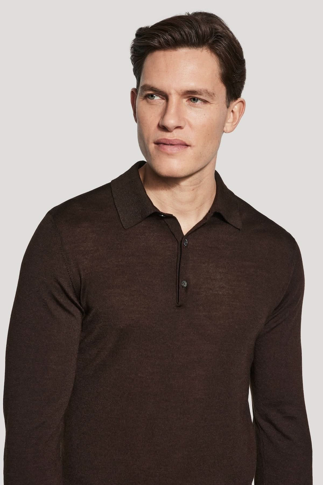 Homme portant un polo manches longues en laine mérinos et soie, couleur marron, avec un col classique élégant.