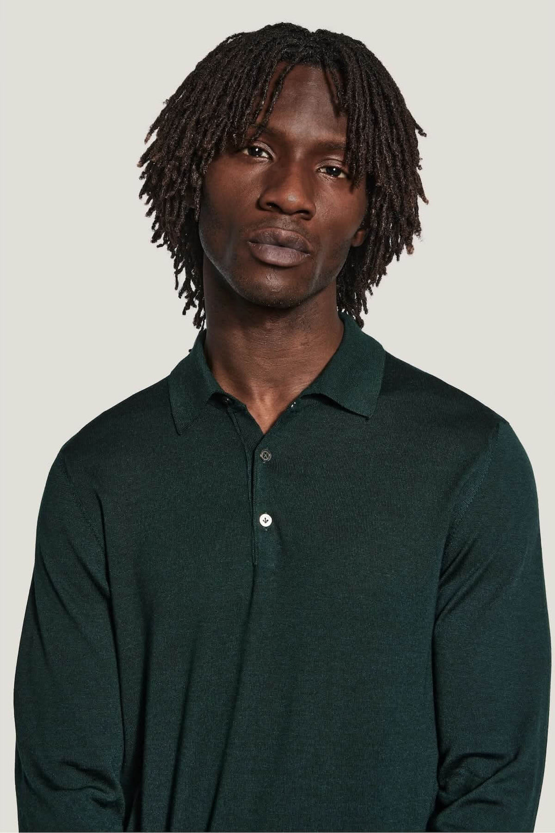 Homme portant un polo manches longues en laine mérinos et soie, couleur vert foncé, coupe ajustée, élégant et moderne.