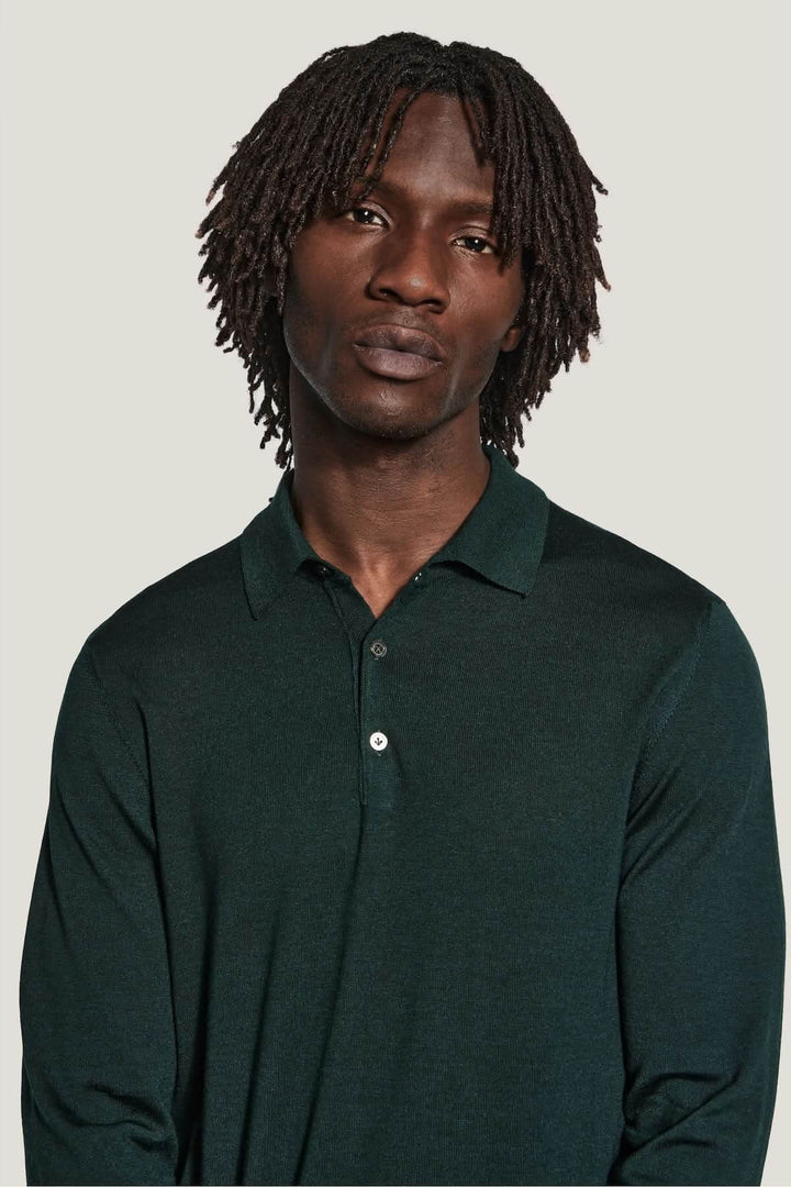 Homme portant un polo manches longues en laine mérinos et soie, couleur vert foncé, coupe ajustée, élégant et moderne.