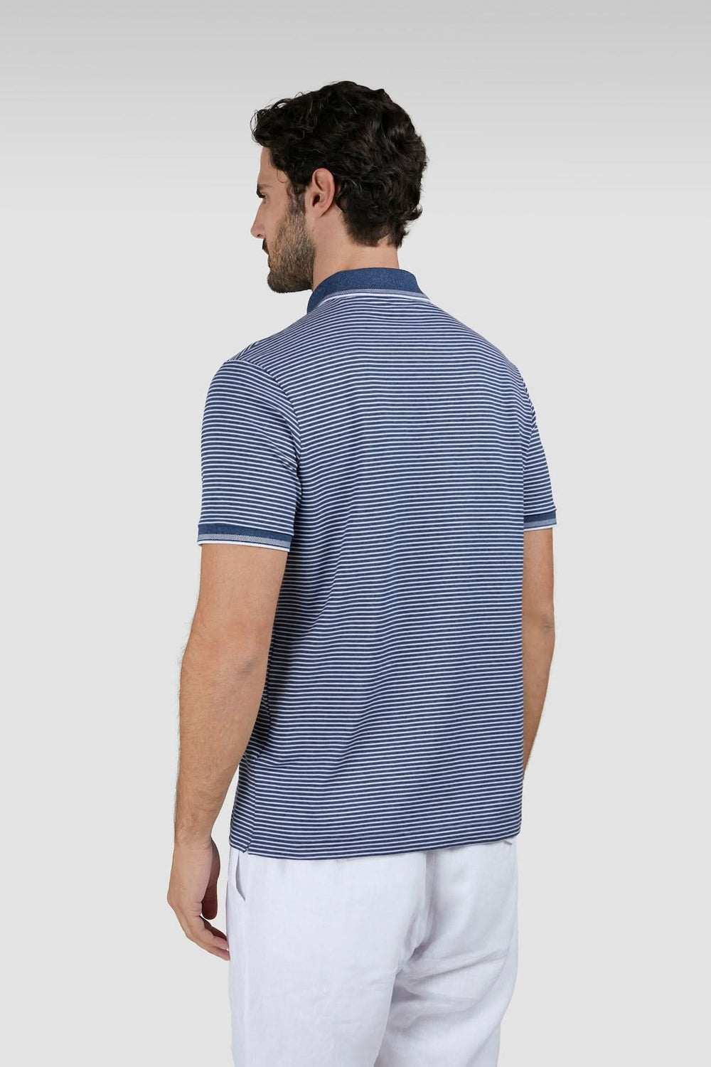 Homme portant un Polo rayé en coton piqué Jaspe, vu de dos, couleur bleu, pour un style estival élégant et intemporel.