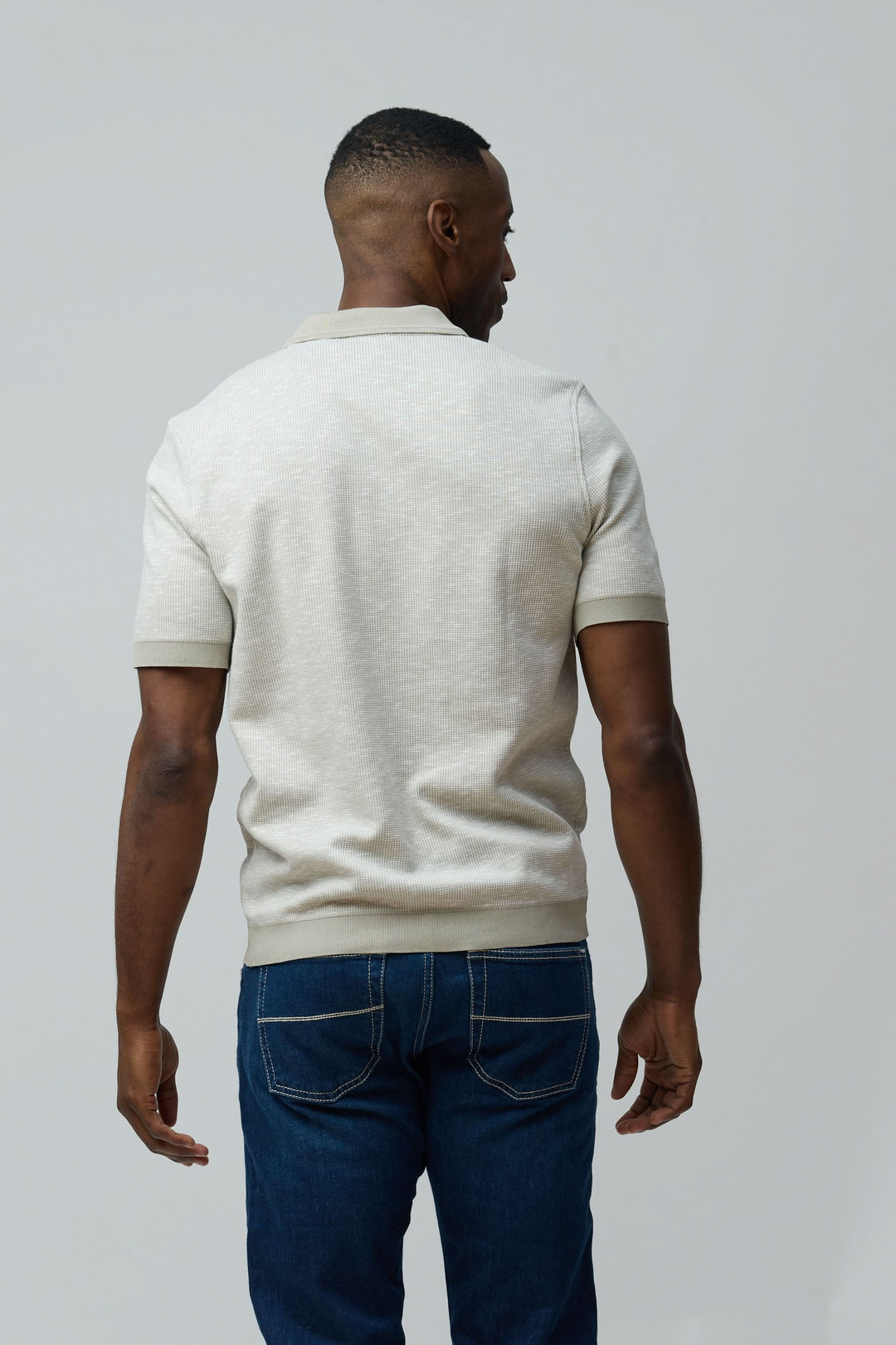 Homme portant un Polo texturé à fermeture zippée en coton peigné et flammé avec un look décontracté, vue de dos.