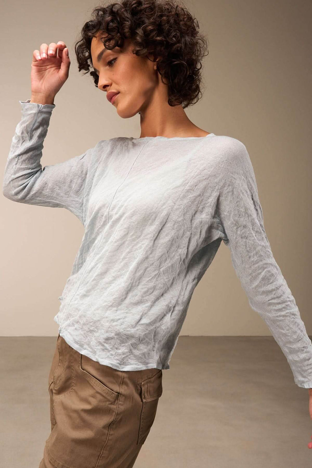 Pull clair léger avec texture froissée, manches longues, porté avec pantalon cargo marron pour un look décontracté.