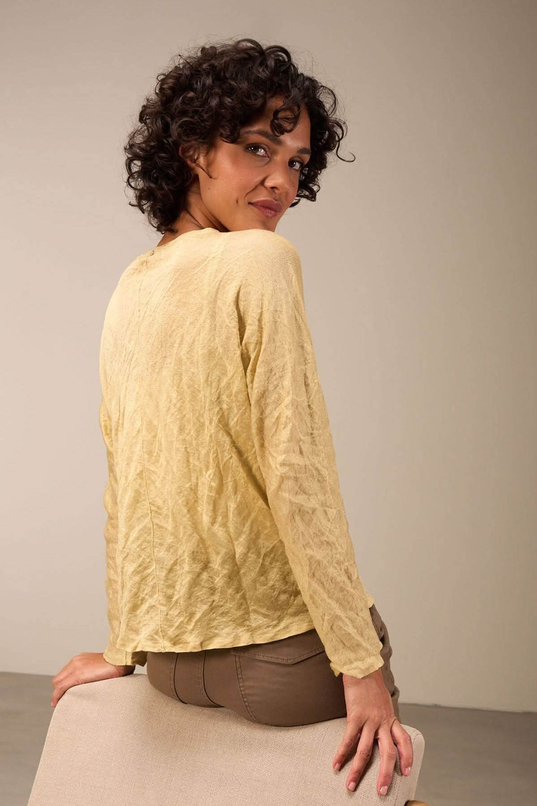 Pull clair à texture froissée sur modèle, porté avec un pantalon beige, pour un look décontracté.