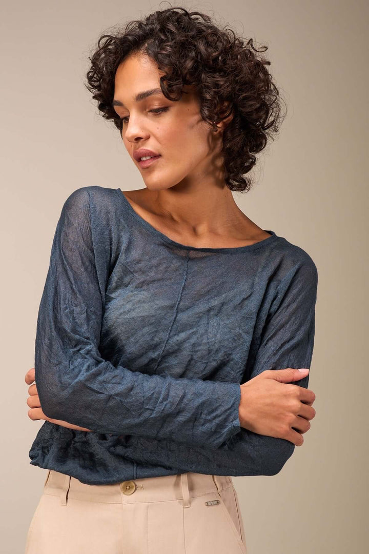Pull léger et décontracté en tissu froissé, avec manches longues et coupe ample, porté par une femme.
