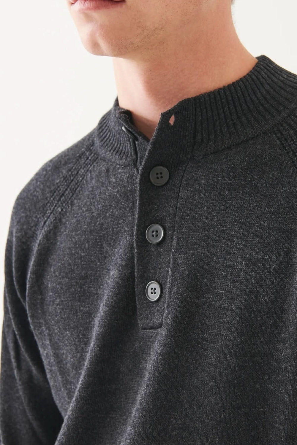 Pull à col boutonné en mérinos, confortable et élégant, avec manches raglan et encolure distinctive.
