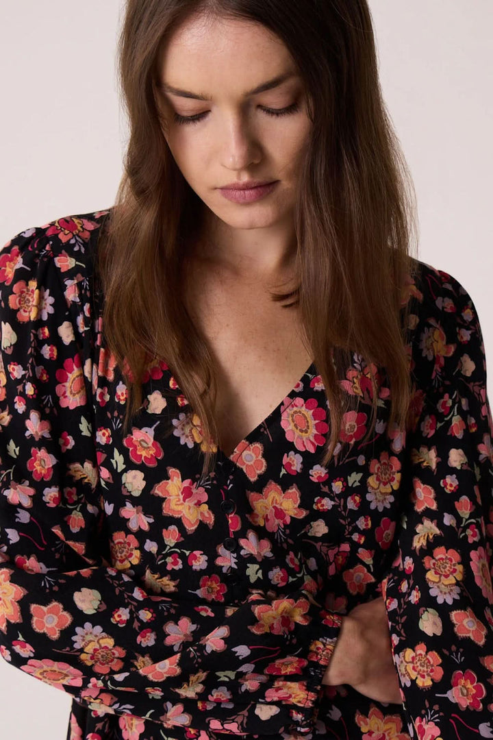 Femme portant la robe Eliota en fleurs avec décolleté V et manches longues, parfaite pour l'automne.