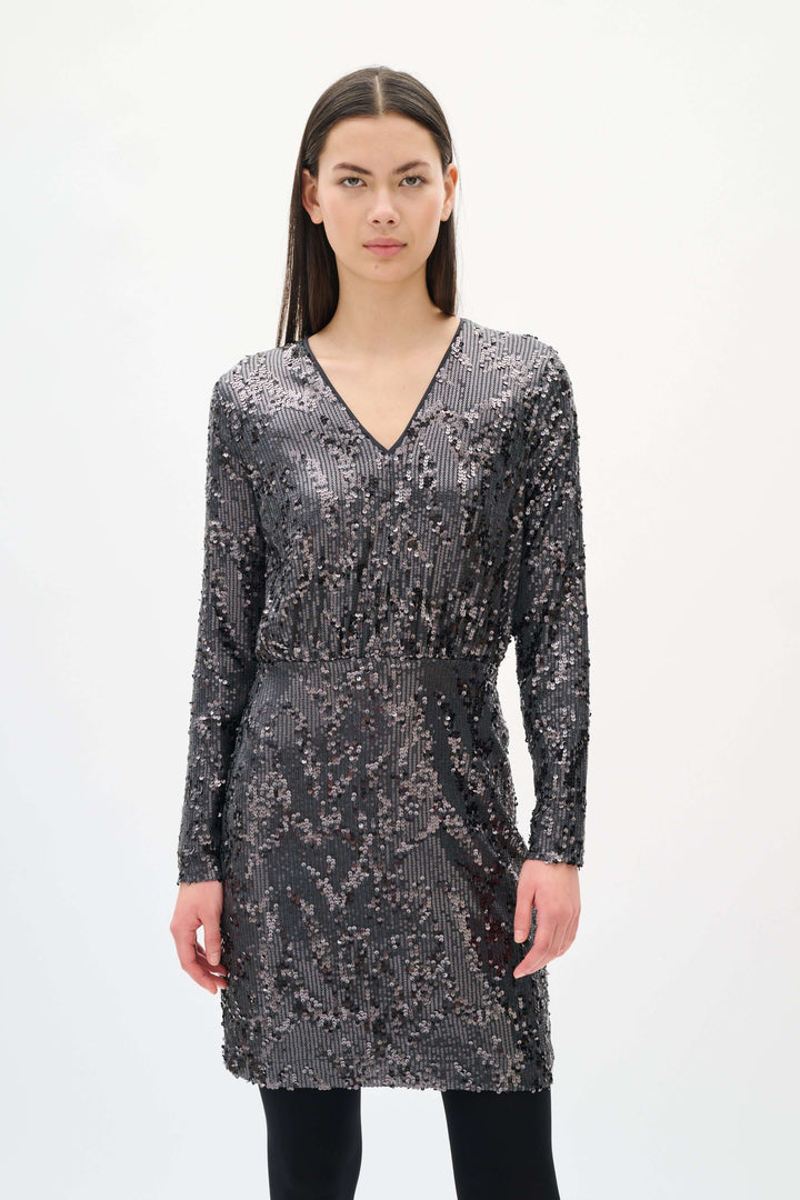 Femme portant la Robe Kimba à paillettes à manches longues avec col en V et taille cintrée, idéale pour soirées festives.